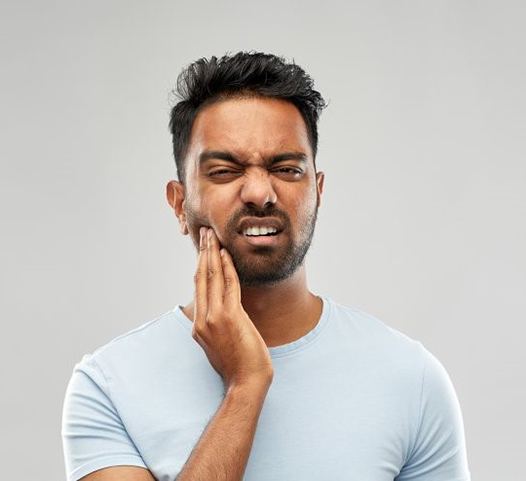 Pained man with hand on cheek should visit his emergency dentist 