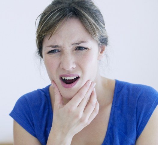 Woman in need of T M J therapy holding jaw