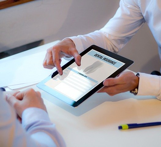 Patient and dentist looking at dental insurance forms on tablet computer