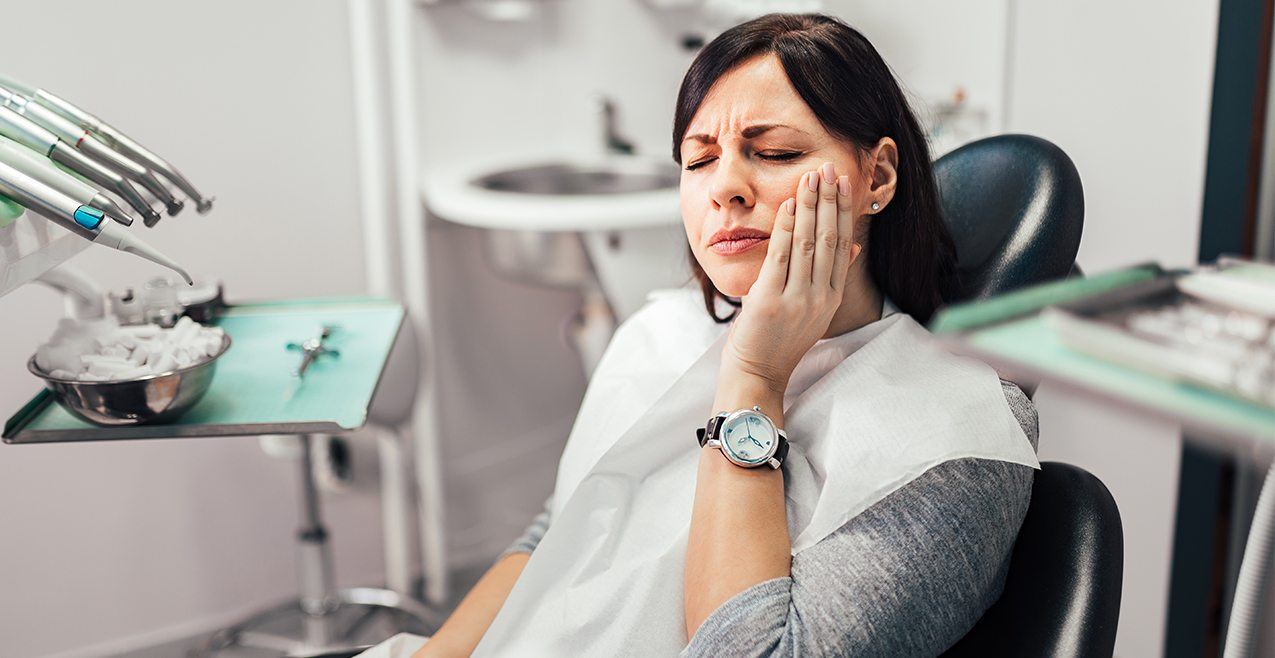 Woman in need of root canal holding cheek