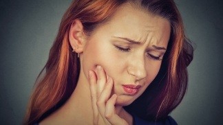 Woman in need of emergency dentistry holding cheek